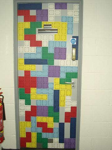 A door covered in pieces of paper, shaped and looking like Netris blocks.